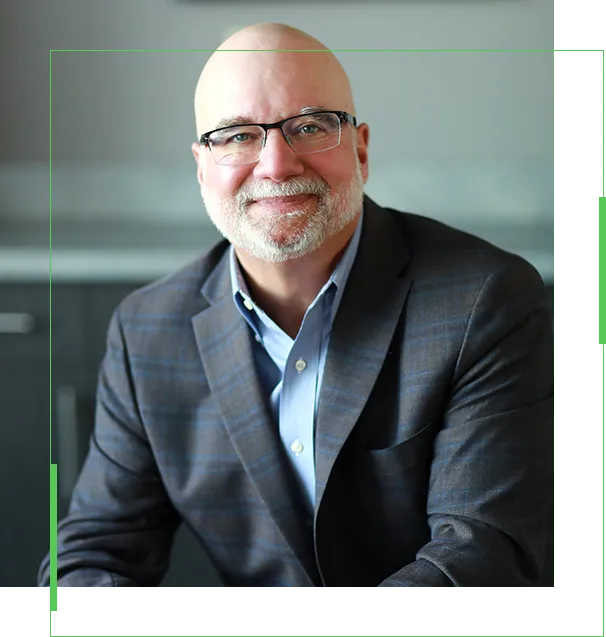 A man in a suit and glasses sitting down.