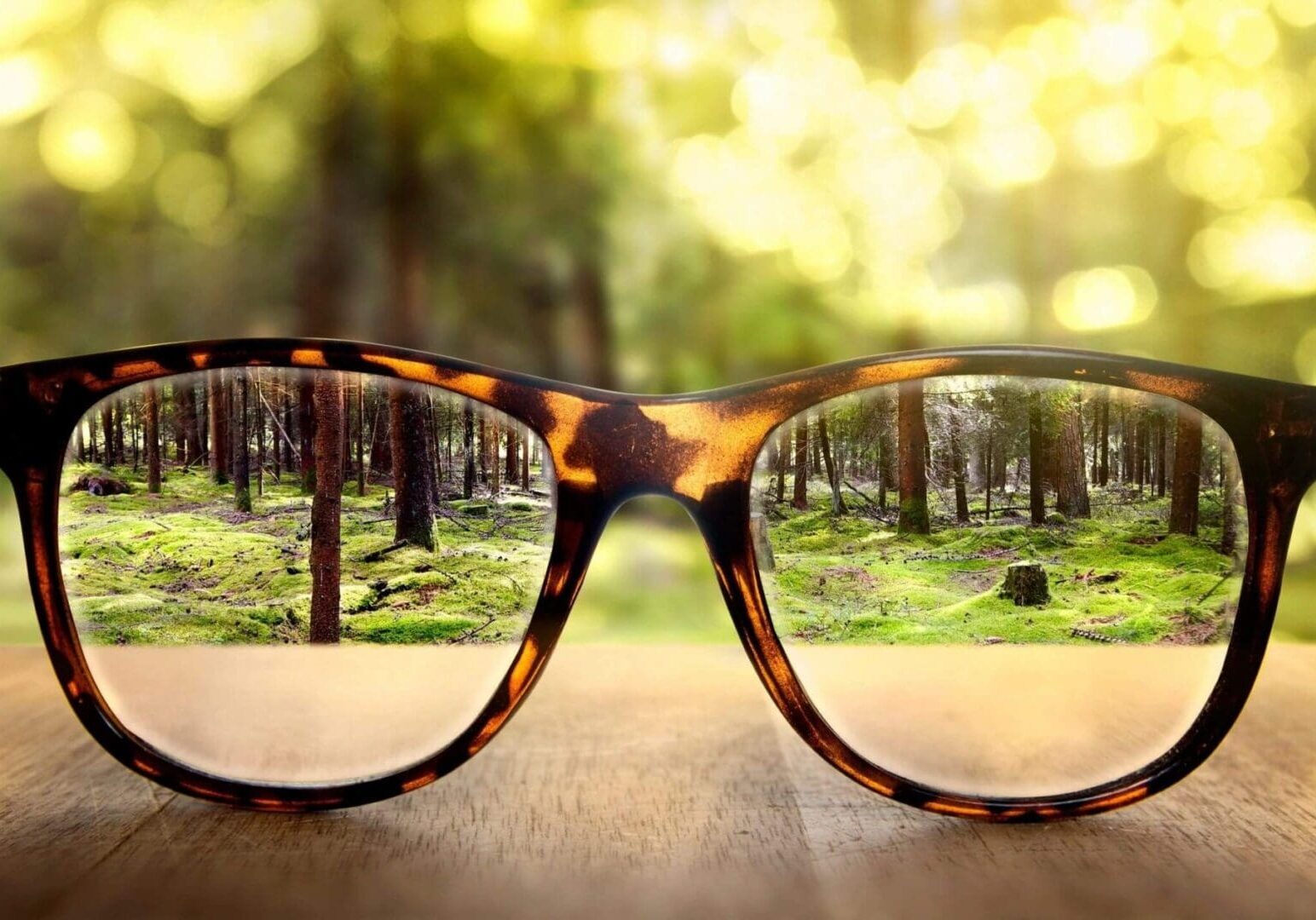 A pair of glasses sitting on top of a wooden table.